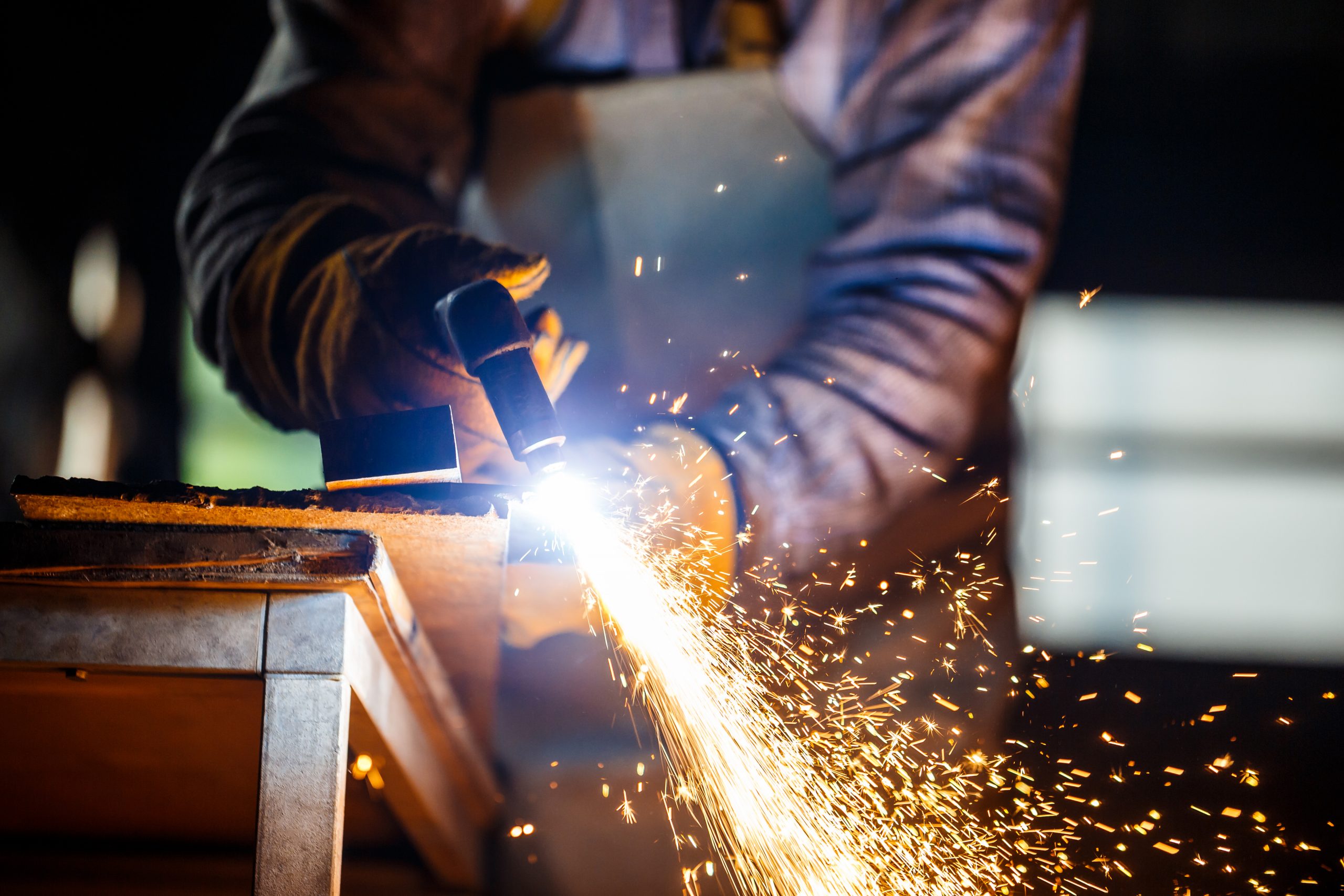 Man Cutting metal using new advanced manufacturing techniques and tools